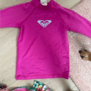 Roxy Girls' Bright Pink Long-Sleeve Rashguard with Striped Heart Logo.